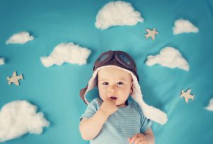 boy lying on blanket with white clouds in pilot hat